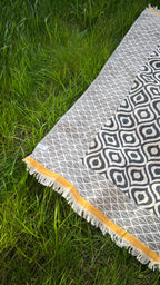 Bohemian-style area rug, black and white geometric patterns, fringed edges with mustard yellow trim.