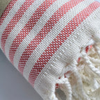 Weavico orange and white striped Turkish beach towel made of 100% cotton with fringe detail.